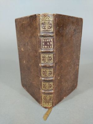 an old book sitting on top of a table next to a white wall