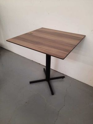 a wooden table with a black metal base in a room