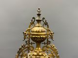 a gold clock on a stand with a sky background