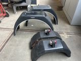 four black fenders sitting on the floor in a garage