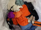 a pile of clothes in a white bag with a suitcase