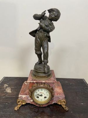 figurine en bronze représentant un garçon tenant un oiseau, posée sur un socle en marbre