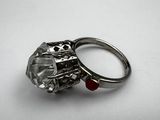 a close up of a ring with a diamond and a red bead