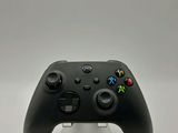 a close up of a black controller on a white surface