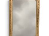 un miroir à cadre doré accroché à un mur blanc, avec un ciel nuageux en arrière-plan