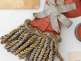 a red bag with a tassel on it next to a book and a candle