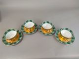 four cups and saucers with green and white designs on them