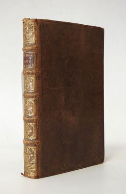 un vieux livre à la couverture brune posé sur une surface blanche