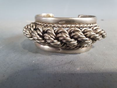 une bague en argent ornée d'un motif de corde torsadée, posée sur une table