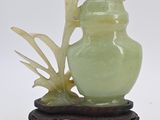un vase vert orné d'une feuille, posé sur un socle