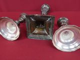 trois bougeoirs anciens en métal argenté posés sur un tissu rouge