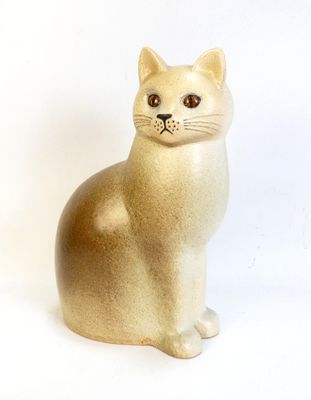 beige cat figurine sitting on a white surface with a white background