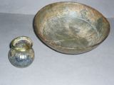 a metal bowl and a glass vase sitting on a table