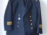 veste bleu marine avec des boutons dorés et des bordures dorées, suspendue à un cintre