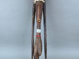 une vieille statue en bois représentant un homme aux cheveux longs et coiffé d'un chapeau