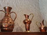 three copper vases sitting on a shelf in a room
