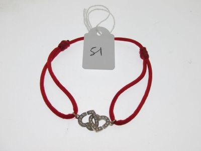 bracelet en fil rouge orné d'une breloque en forme de cœur en argent sur fond blanc