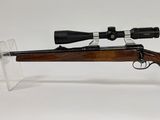 le fusil est posé sur un support transparent et est équipé d'une lunette de visée