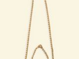 a gold chain necklace with a triangle shaped pendant on a white background