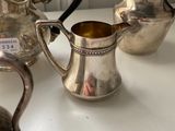 three silver teapots on a white table with a window in the background