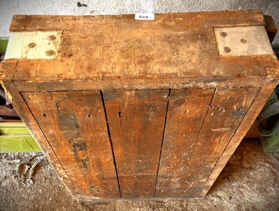 une vieille boîte en bois posée par terre à côté d'une plante