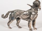 statue en argent représentant un chien tenu en laisse sur fond blanc