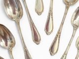 six silver spoons are arranged in a circle on a white surface