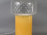 a yellow table lamp with a clear glass shade on top of it