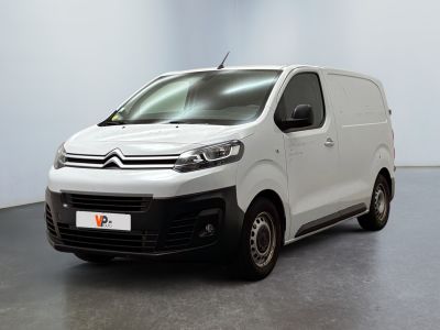 La camionnette blanche est garée dans une pièce au sol gris.