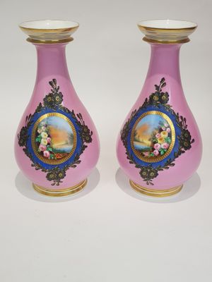 une paire de vases roses ornés d'une bordure dorée et représentant une femme dans un jardin