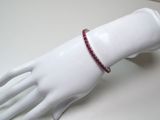 une main de mannequin blanche à laquelle est attaché un bracelet rouge