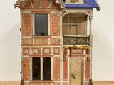 a wooden doll house with a blue roof on a wooden table