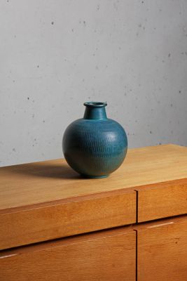 a blue vase sitting on top of a wooden dresser