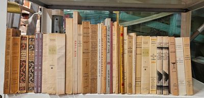 de nombreux livres posés sur une étagère près d'une fenêtre