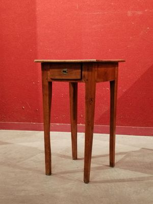 a small table with a drawer on it in front of a red wall