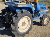 a blue tractor that is parked in the dirt