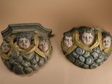 pair of decorative wall plaques with faces on them on a beige background
