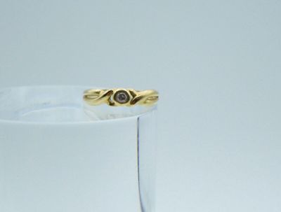 a gold ring with a diamond in it sitting on a glass