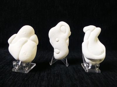 three figurines of birds that are sitting on a stand