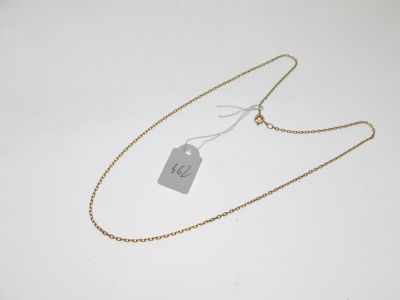 a gold necklace with a tag on it sitting on a white surface