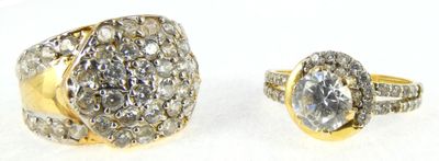 two gold rings with diamonds on a white background