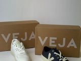 une paire de baskets blanches et bleues posée à côté d'une boîte de chaussures Vejaa