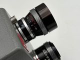 an old camera with a lens attached to it on a white surface