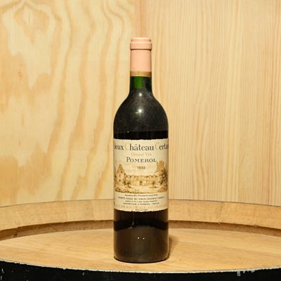 a bottle of wine sitting on top of a wooden barrel