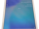 a white tablet with a blue screen on a white table