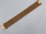 a gold bracelet with a metal clasp on a white surface
