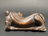 bronze statue of a woman laying on a pillow on a black surface
