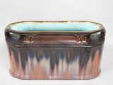 une jardinière marron et bleue posée sur une surface blanche