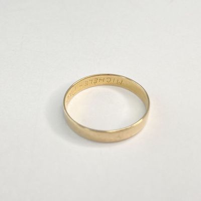 gros plan d'une bague en or sur une surface blanche