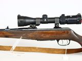 the rifle is sitting on a wooden stand with a scope on it